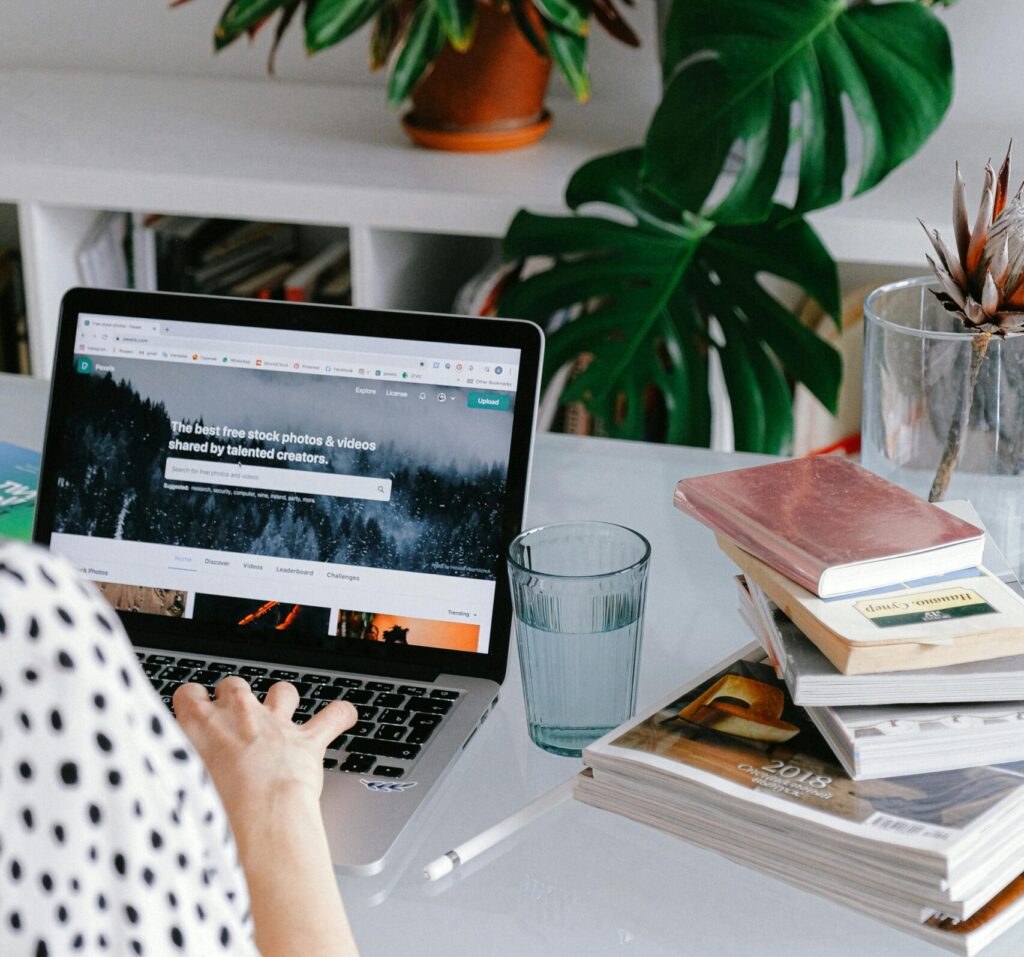 A woman working from home on her laptop surrounded by plants and books for a cozy office feel.